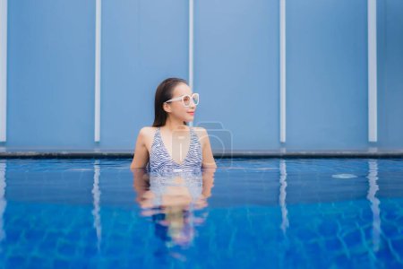 Téléchargez les photos : Portrait belle jeune femme asiatique se détendre sourire autour de la piscine extérieure pour des vacances de loisirs - en image libre de droit