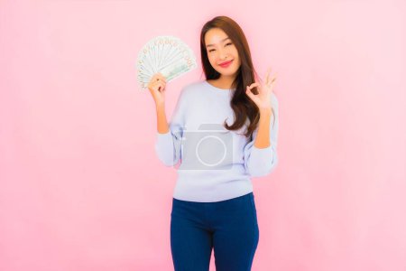 Foto de Retrato hermosa joven asiática mujer con un montón de dinero en efectivo y dinero en rosa color de fondo - Imagen libre de derechos