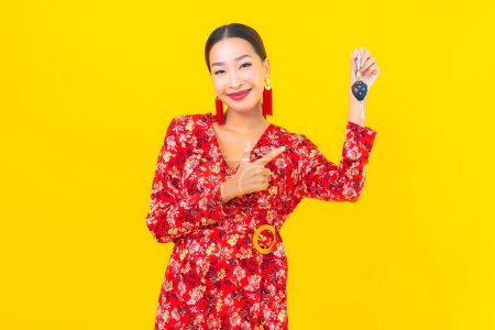 Téléchargez les photos : Portrait belle jeune femme asiatique avec clé de voiture sur fond jaune - en image libre de droit