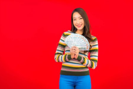 Photo for Portrait beautiful young asian woman with cash money and mobile phone on red background - Royalty Free Image