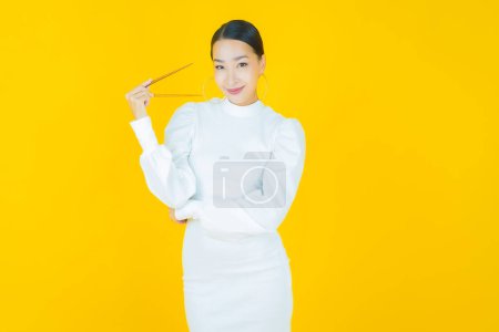 Téléchargez les photos : Portrait belle jeune femme asiatique avec baguettes sur fond de couleur - en image libre de droit