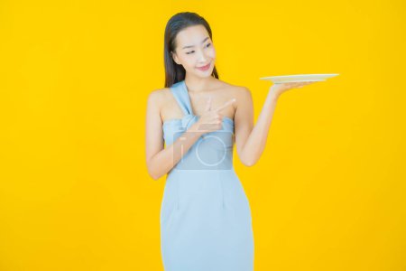 Photo for Portrait beautiful young asian woman smile with empty plate dish on color background - Royalty Free Image
