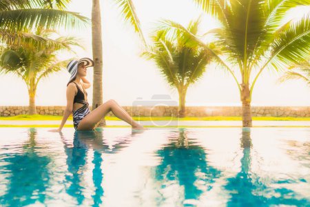 Photo for Portrait beautiful young asian woman relax around outdoor swimming pool in hotel resort with palm tree at sunset or sunrise for leisure vacation - Royalty Free Image