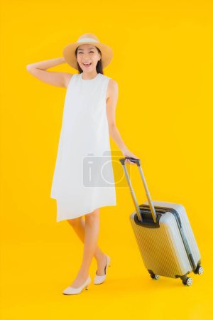 Téléchargez les photos : Portrait belle jeune femme asiatique concept de voyage avec bagages sur fond jaune isolé - en image libre de droit