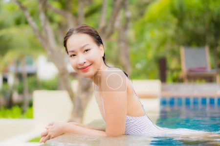 Téléchargez les photos : Portrait belle jeune femme asiatique sourire se détendre autour de la piscine extérieure en hôtel de villégiature en voyage vacances - en image libre de droit