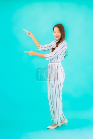 Téléchargez les photos : Portrait belle jeune femme asiatique sourire en action sur fond bleu isolé - en image libre de droit