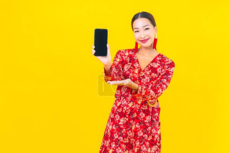 Foto de Retrato hermosa joven asiático mujer uso inteligente móvil en amarillo color fondo - Imagen libre de derechos
