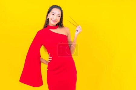 Foto de Retrato hermosa joven asiática mujer con palillo listo para comer sobre fondo amarillo - Imagen libre de derechos