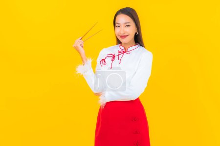Téléchargez les photos : Portrait belle jeune femme asiatique avec baguette prête à manger sur fond jaune - en image libre de droit