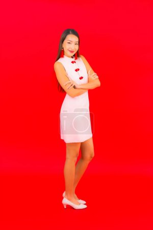 Téléchargez les photos : Portrait belle jeune femme asiatique porter des vêtements du Nouvel An chinois sur fond rouge - en image libre de droit
