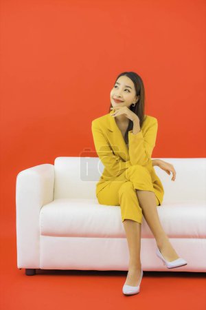 Photo for Portrait beautiful young asian woman sit on sofa chair on red background - Royalty Free Image