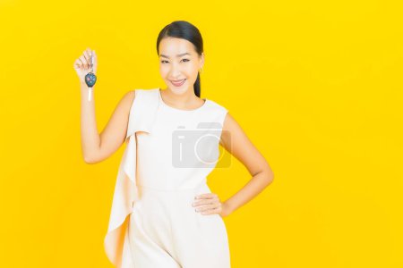 Photo for Portrait beautiful young asian woman smile with car key on yellow color background - Royalty Free Image