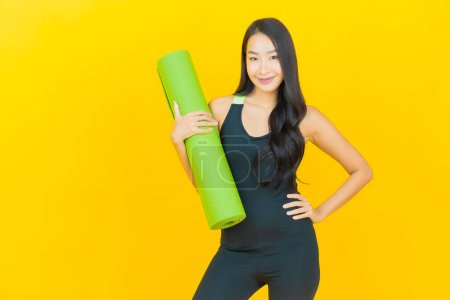Téléchargez les photos : Portrait belle jeune femme asiatique porter tenue de gym prêt pour l'exercice sur fond de couleur jaune - en image libre de droit
