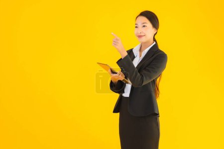 Photo for Portrait beautiful young asian woman happy smile with smart tablets device on yellow isolated background - Royalty Free Image