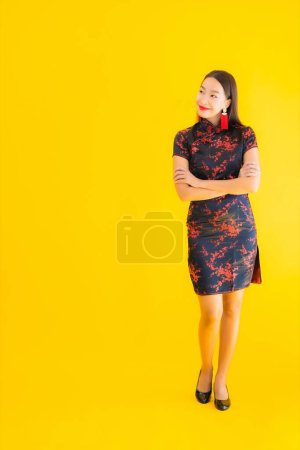 Téléchargez les photos : Portrait belle jeune femme asiatique porter robe chinoise avec action pour le nouveau concept de l'année chinoise sur fond jaune isolé - en image libre de droit
