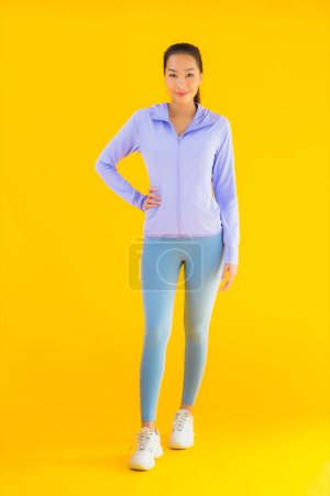 Foto de Retrato hermosa joven asiática deporte mujer con ropa deportiva listo para el ejercicio en amarillo aislado fondo - Imagen libre de derechos