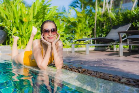 Foto de Retrato hermosa joven mujer asiática relajarse sonrisa feliz alrededor de la piscina al aire libre en el complejo hotelero para vacaciones de ocio - Imagen libre de derechos