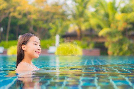 Téléchargez les photos : Portrait belle jeune femme asiatique relax sourire loisirs autour de la piscine extérieure presque mer plage océan pour vacances - en image libre de droit