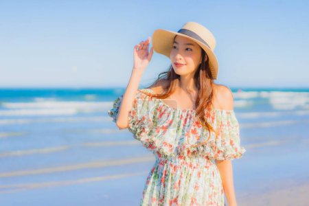 Téléchargez les photos : Portrait belle jeune femme asiatique sourire heureux se détendre autour de la plage tropicale mer océan sur ciel bleu pour les loisirs - en image libre de droit