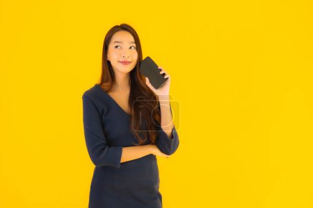 Foto de Retrato hermosa joven asiática mujer con teléfono móvil inteligente o teléfono celular en amarillo aislado fondo - Imagen libre de derechos