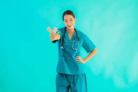 Foto de Retrato hermosa joven asiática médico mujer con píldora o droga y medicina en azul aislado fondo - Imagen libre de derechos