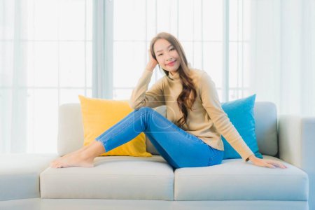 Téléchargez les photos : Portrait belle jeune femme asiatique se détendre loisirs profiter sur canapé dans le salon espace intérieur - en image libre de droit