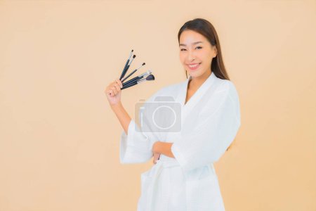 Téléchargez les photos : Portrait belle jeune femme asiatique avec pinceau de maquillage sur fond isolé couleur - en image libre de droit