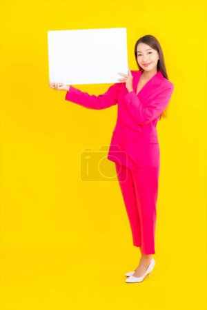 Téléchargez les photos : Portrait belle jeune femme asiatique avec panneau d'affichage blanc vide sur fond jaune isolé - en image libre de droit
