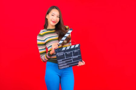 Photo for Portrait beautiful young asian woman with movie slate cutting on red isolated background - Royalty Free Image
