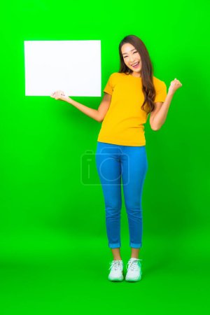Foto de Retrato hermosa joven asiática mujer show blanco vacío valla publicitaria en verde color fondo - Imagen libre de derechos