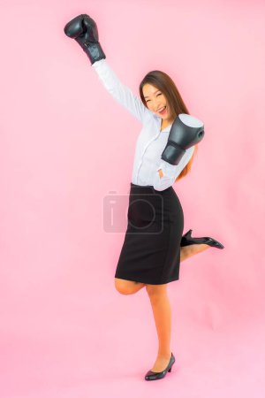 Téléchargez les photos : Portrait belle jeune femme asiatique avec gant de boxe prêt à se battre sur fond rose - en image libre de droit
