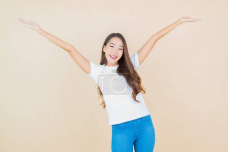 Téléchargez les photos : Portrait belle jeune femme asiatique sourire avec action avec fond de couleur crème - en image libre de droit