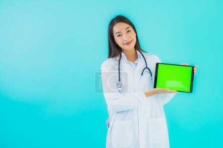 Foto de Retrato hermosa joven asiática médico mujer con estetoscopio y tableta inteligente para su uso en el hospital y la clínica sobre fondo aislado azul - Imagen libre de derechos