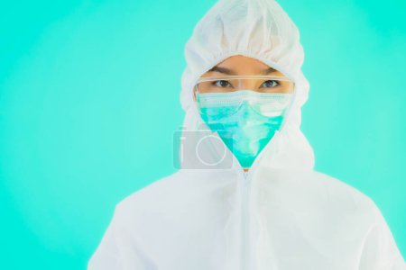 Téléchargez les photos : Portrait belle jeune asiatique médecin femme porter ppe ou équipement de protection individuelle pour protéger contre le coronavirus ou covid19 sur fond bleu isolé - en image libre de droit