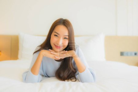 Foto de Retrato hermosa joven asiática mujer relax sonrisa ocio en cama en dormitorio interior - Imagen libre de derechos