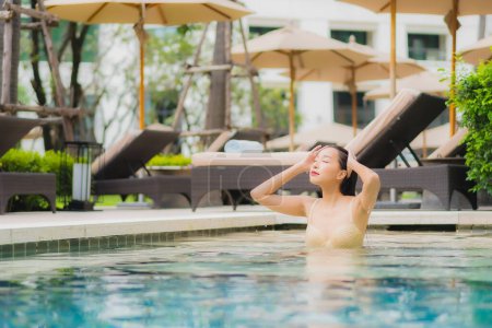 Foto de Retrato hermosa joven mujer asiática relajarse sonrisa alrededor de la piscina al aire libre en el complejo hotelero para vacaciones de viaje - Imagen libre de derechos