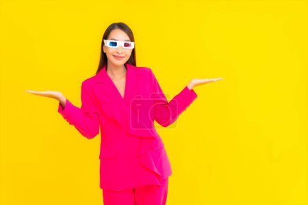 Photo for Portrait beautiful young asian woman wear eyeglasses 3d for watch movie on yellow isolated background - Royalty Free Image