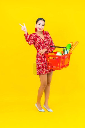 Téléchargez les photos : Portrait belle jeune femme asiatique avec épicerie dans le panier et le chariot du supermarché - en image libre de droit