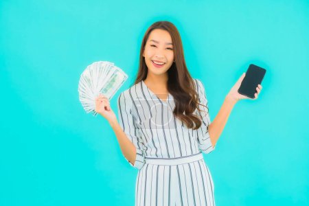 Foto de Retrato hermosa joven asiática mujer con un montón de dinero en efectivo y dinero sobre fondo azul - Imagen libre de derechos