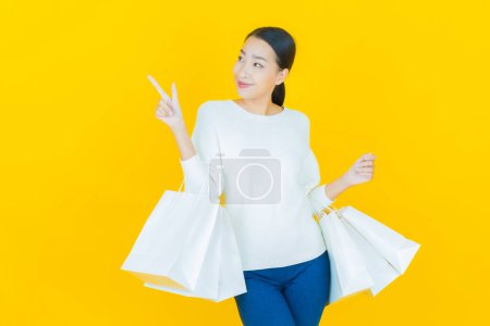 Téléchargez les photos : Portrait belle jeune femme asiatique sourire avec sac à provisions sur fond de couleur - en image libre de droit