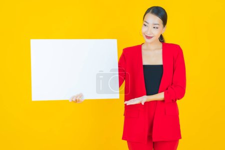 Téléchargez les photos : Portrait belle jeune femme asiatique avec panneau blanc vide sur fond de couleur - en image libre de droit