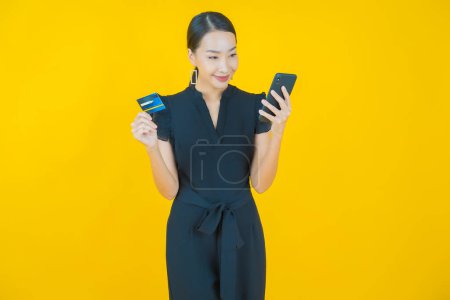 Téléchargez les photos : Portrait belle jeune femme asiatique sourire avec carte de crédit sur fond de couleur - en image libre de droit