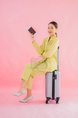 Téléchargez les photos : Portrait belle jeune femme d'affaires asiatique avec sac à bagages et passeport sur fond de couleur - en image libre de droit