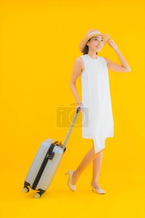 Foto de Retrato hermoso joven asiático mujer viaje concepto con equipaje en amarillo aislado fondo - Imagen libre de derechos