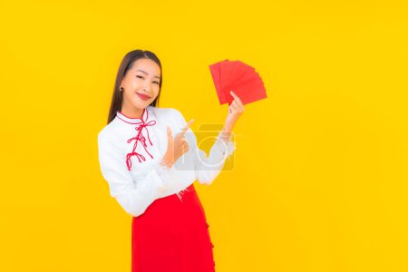 Foto de Retrato hermosa joven mujer asiática con sobres rojos carta en chino año nuevo sobre fondo amarillo - Imagen libre de derechos
