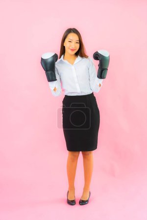 Téléchargez les photos : Portrait belle jeune femme asiatique avec gant de boxe prêt à se battre sur fond rose - en image libre de droit