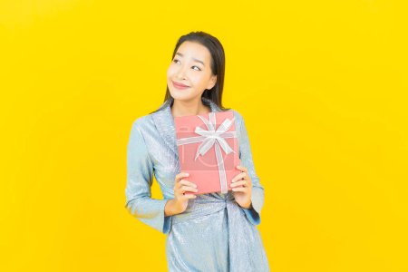 Foto de Retrato hermosa joven mujer asiática sonrisa con caja de regalo roja sobre fondo de color amarillo - Imagen libre de derechos