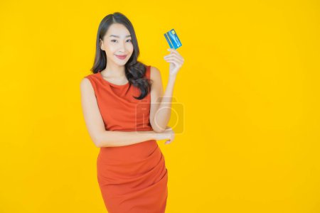 Téléchargez les photos : Portrait belle jeune femme asiatique sourire avec carte de crédit sur fond de couleur - en image libre de droit