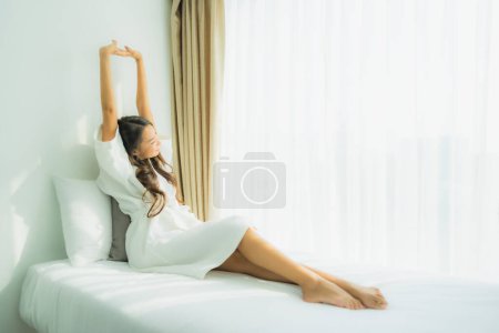 Téléchargez les photos : Jeune femme asiatique sourire heureux se détendre sur le lit dans la chambre intérieure - en image libre de droit