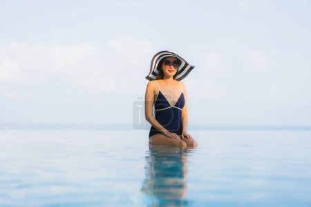 Téléchargez les photos : Portrait belle jeune femme asiatique se détendre autour de la piscine dans la station de l'hôtel pour les loisirs en vacances - en image libre de droit